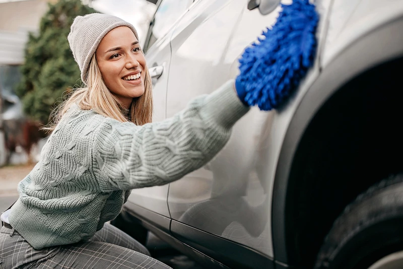 A woman cleaning the outside of her car