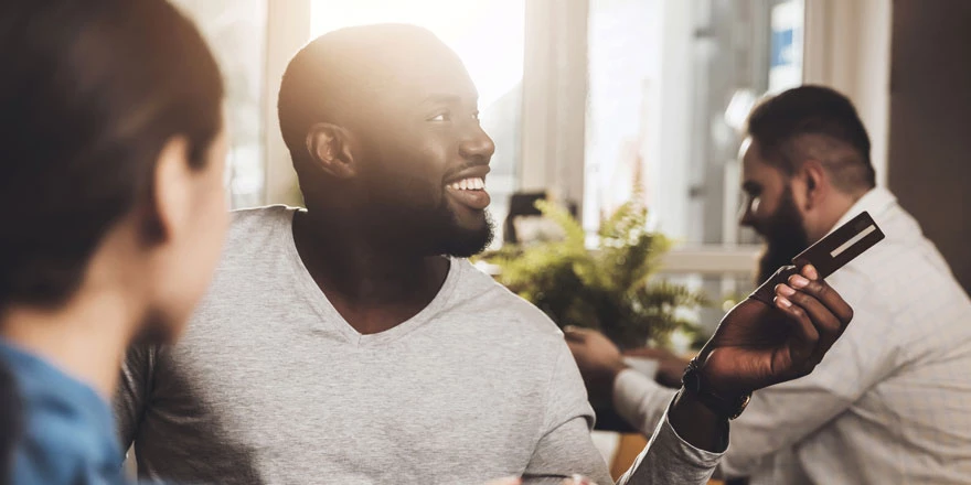 A young man is using his First Midwest debit card to make a purchase