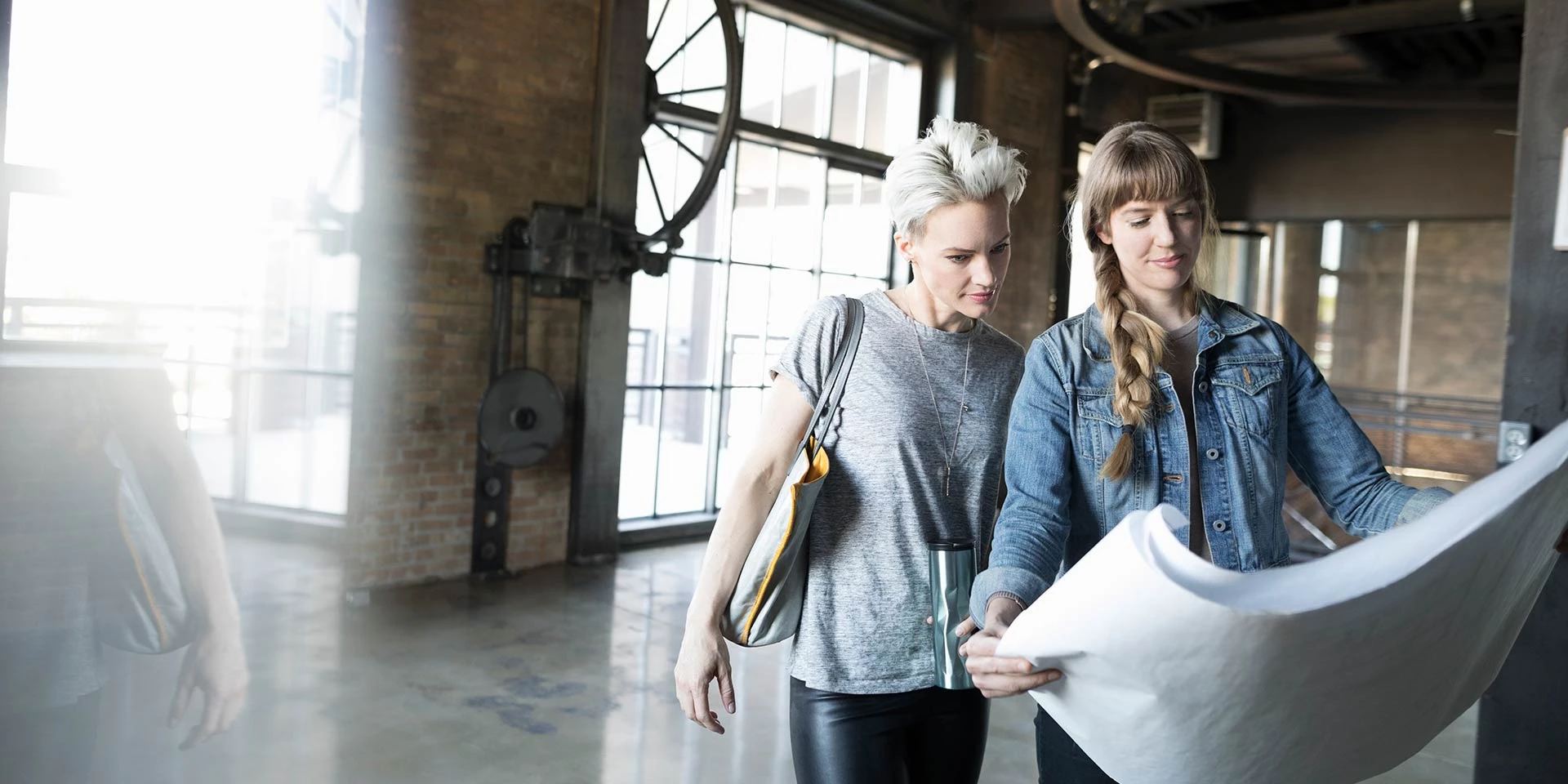 Two businesswomen who received a Real Estate Loan to build a business location are looking over the blueprints