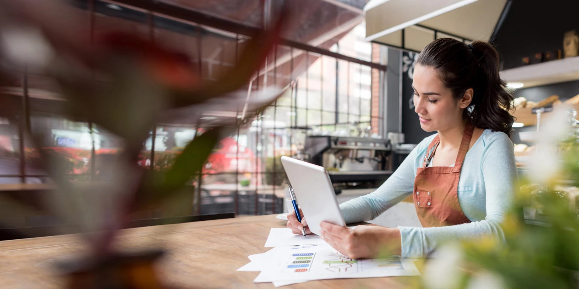 A businesswoman works on a laptop in a new coffee shop she opened with capital received from franchise banking financing