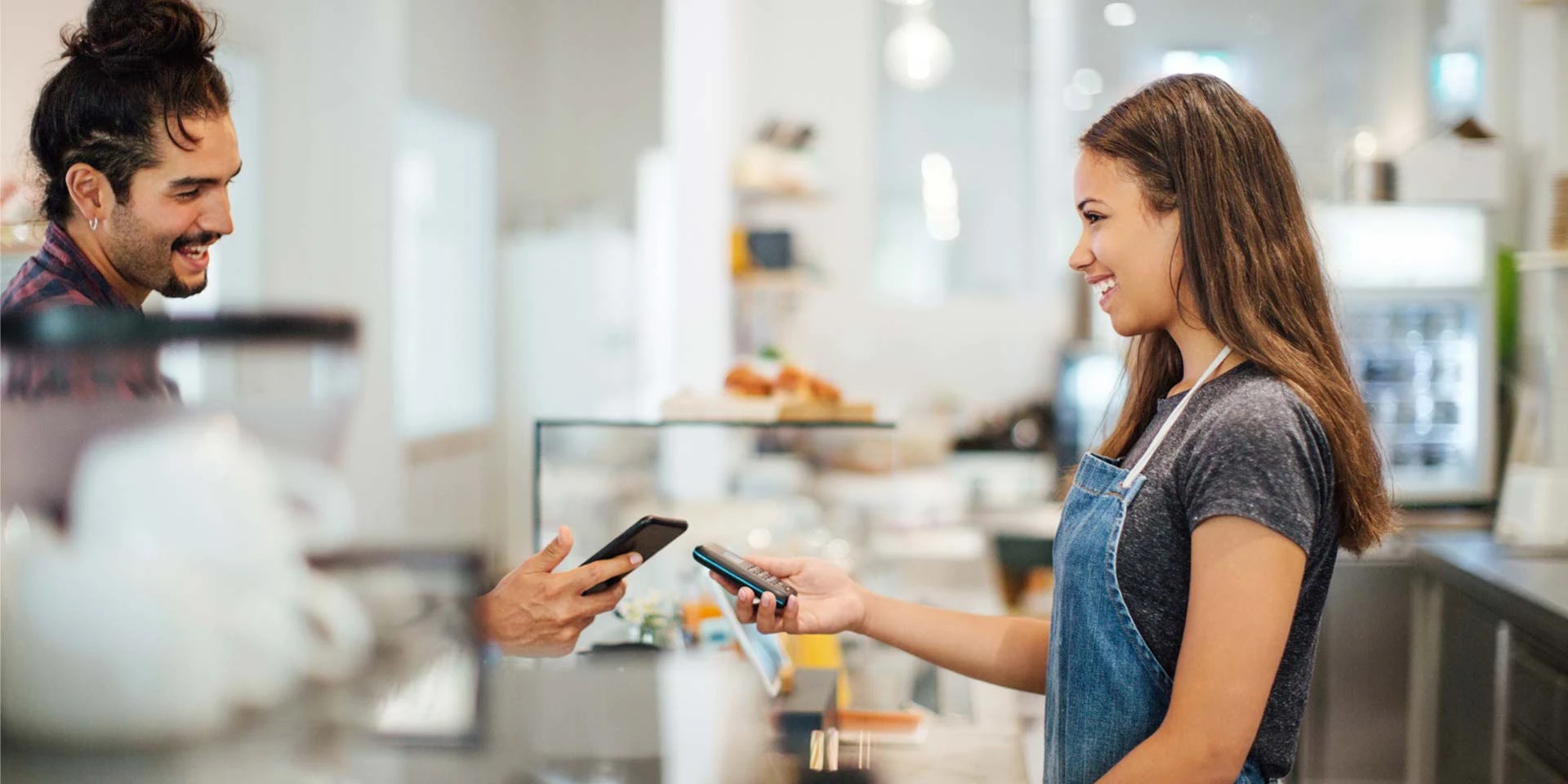 A man makes a payment with his phone to a store owner who uses account receivables payment services