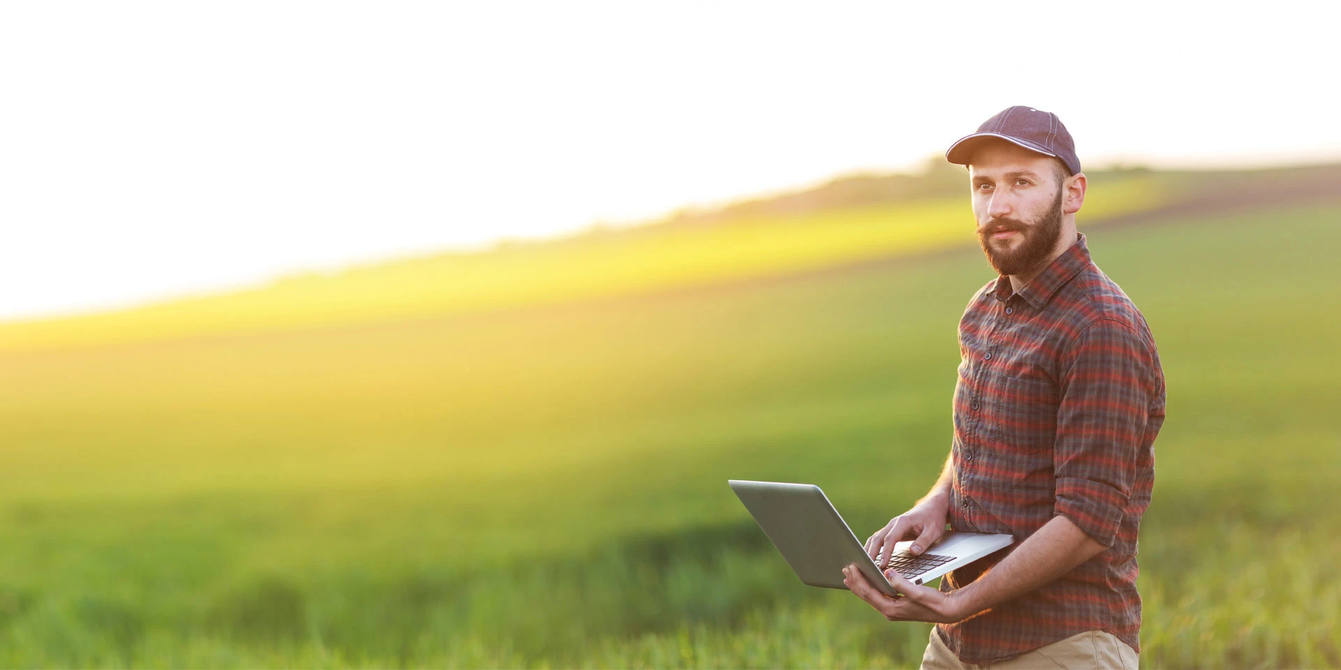 An agricultural business owner stands in a field with a tablet after receiving agribusiness financing and banking services