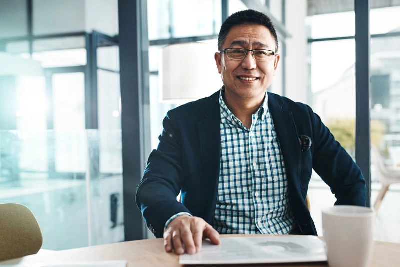 A businessman in a coffee shop reviews information about Treasury Management services on a tablet