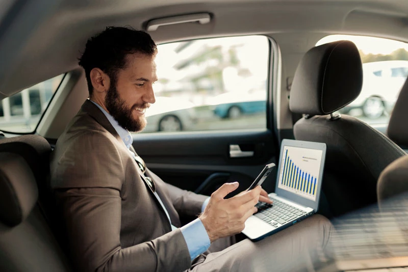 A businessman looks at his phone and laptop and manages his business finances with Liquidity Management tools