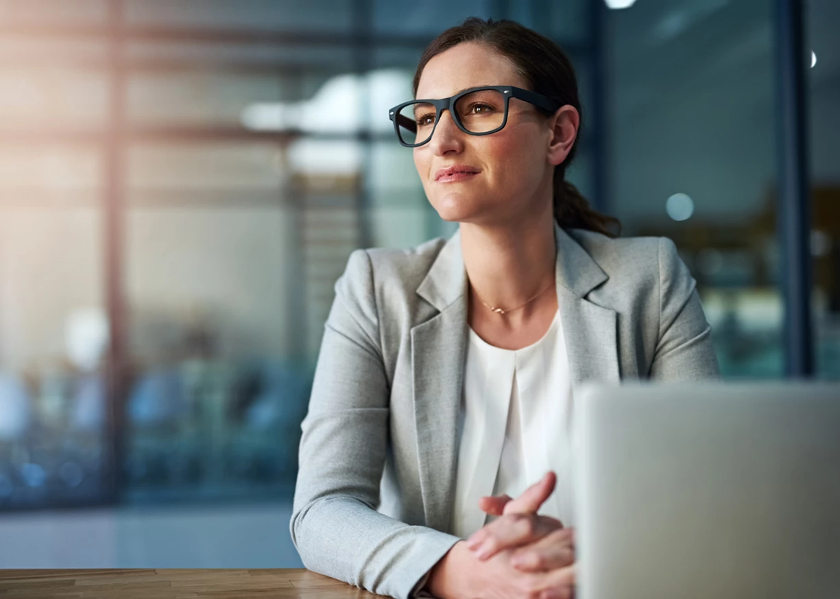 A confident businesswoman in an office with a laptop is researching the best business checking account for her business
