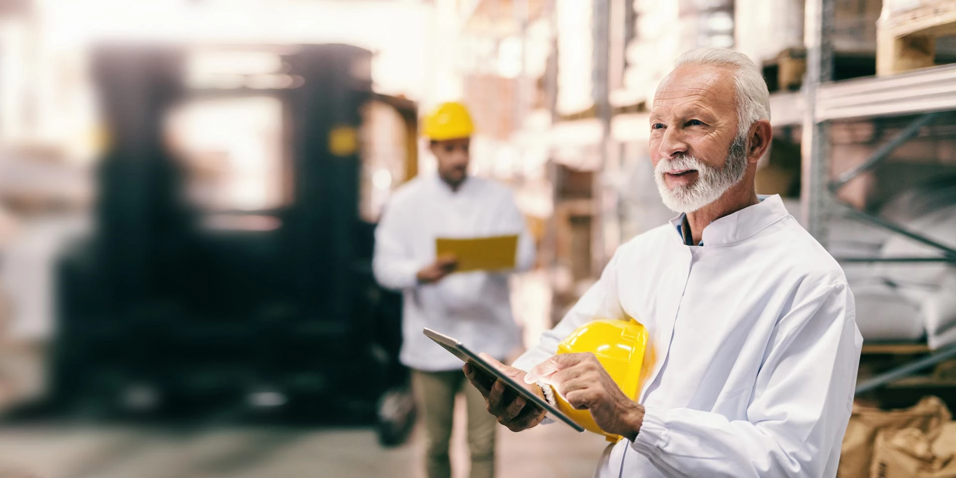 A warehouse manager and his employees are happily working and wearing hard hats after receiving ESOP services