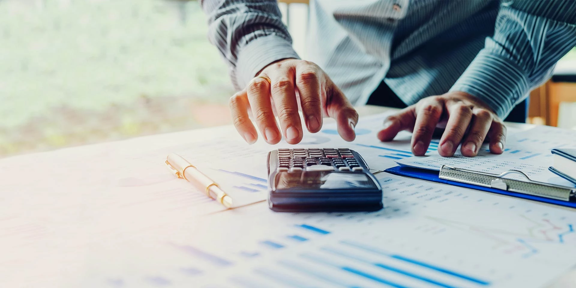 A businessman works over a calculator and financial documents representing business liquidity management