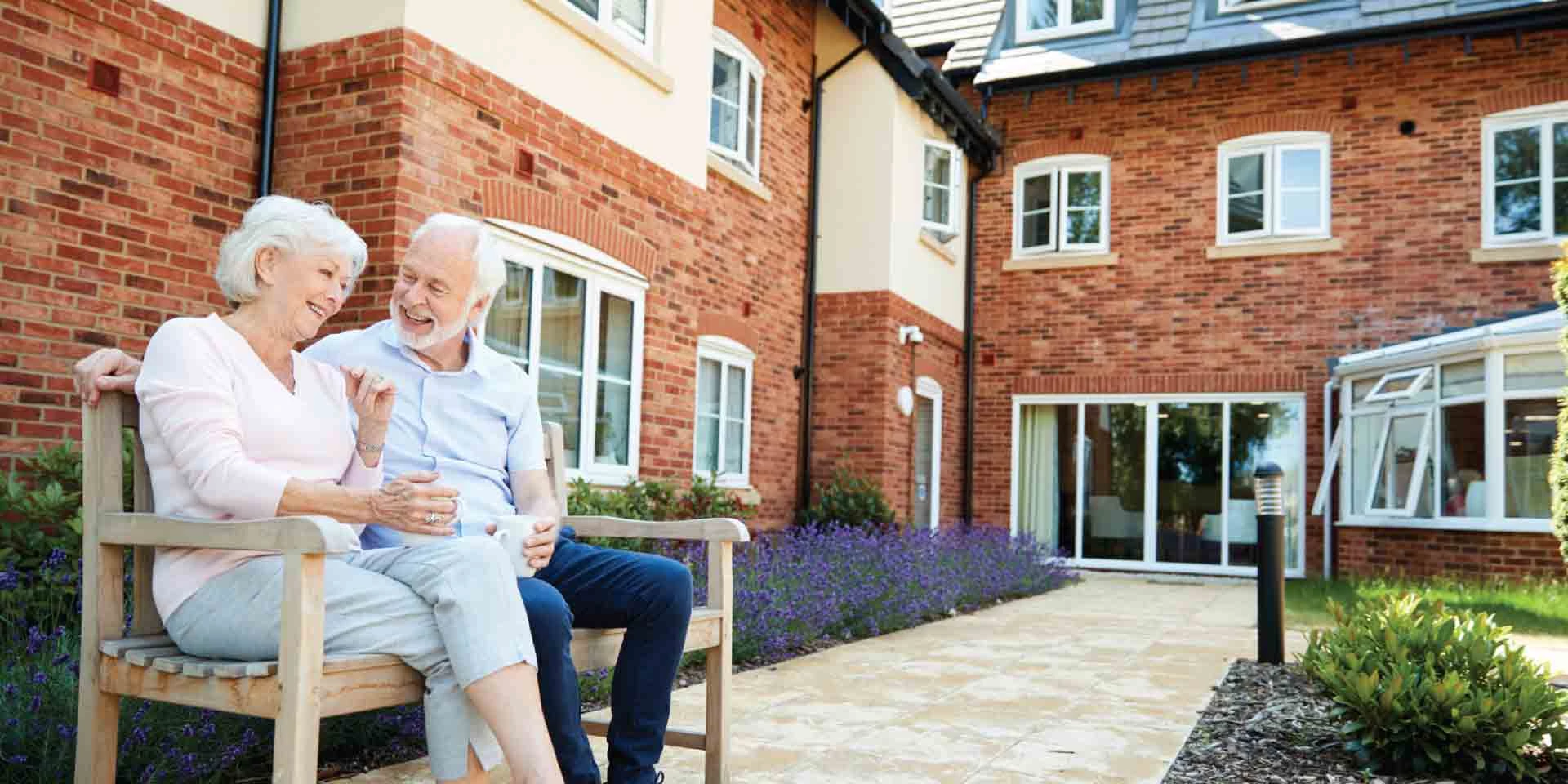 A husband and wife sitting outside on a bench