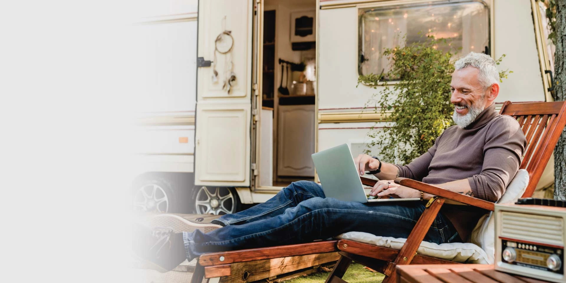 A man outside of his camper looking at his laptop