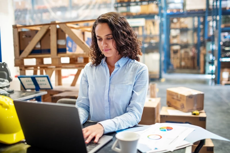 Young professional typing on her computer in a distribution center.