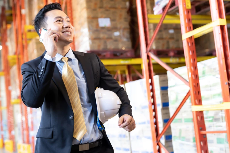 Business professional taking a call on a plant floor.