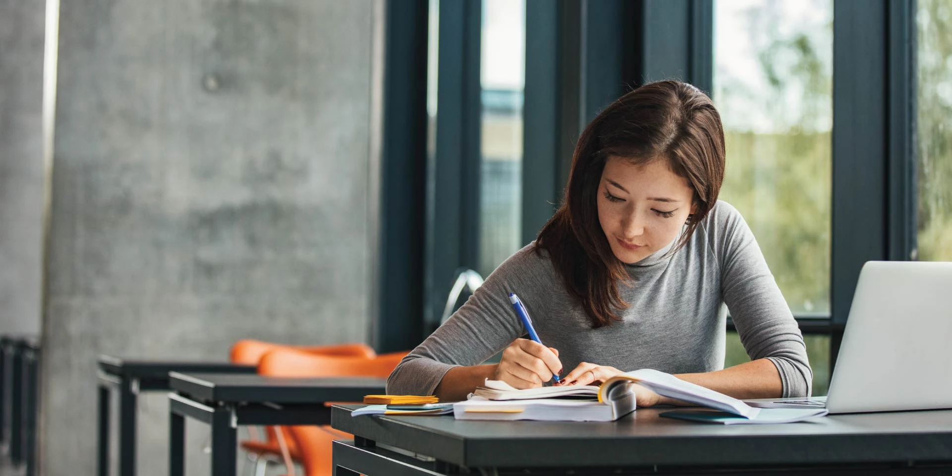 A Student Checking customer who is working in a university library with books and a laptop
