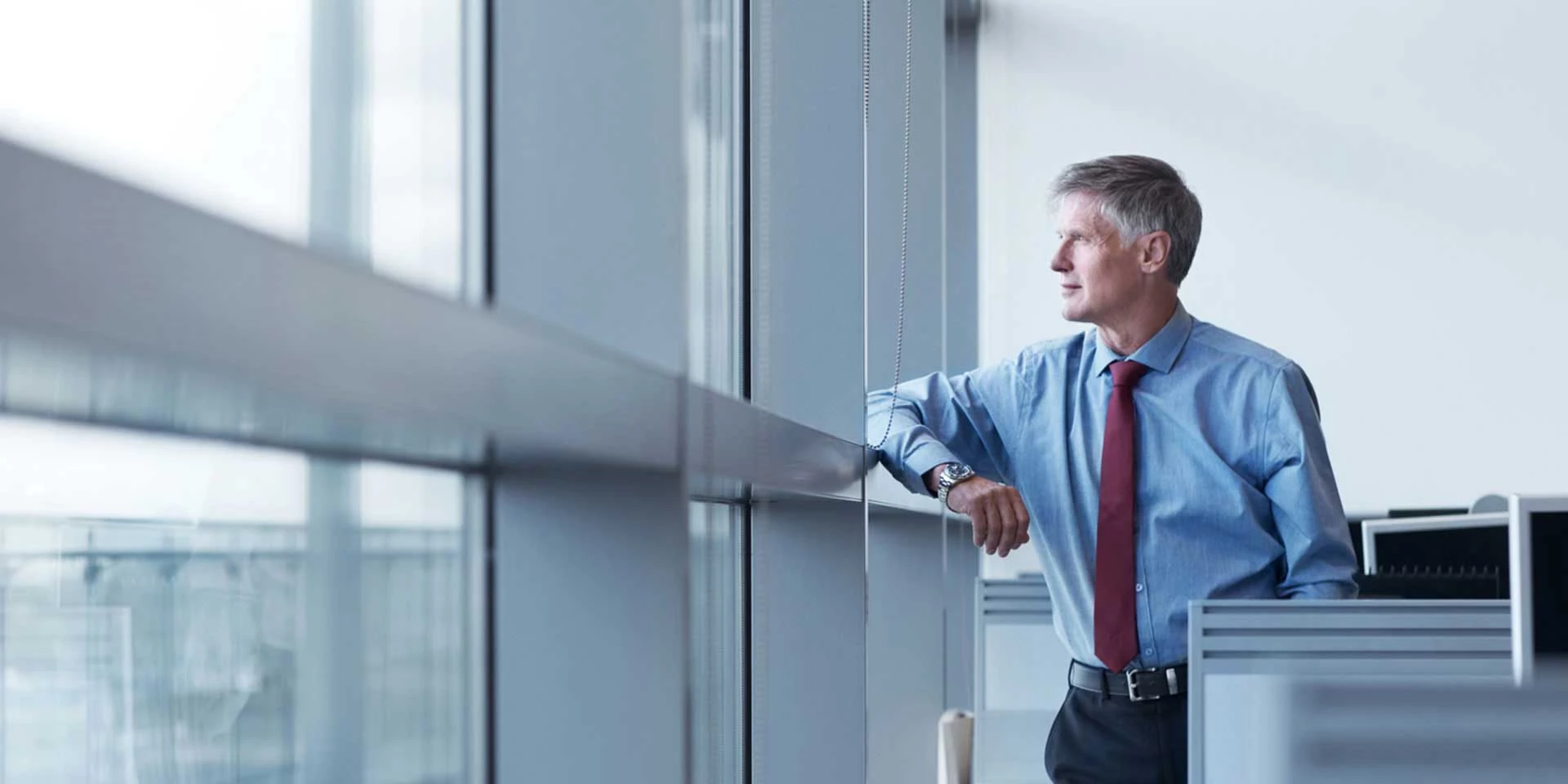 A businessman who has a company utilizing syndications financing confidently looks out his office window over the city